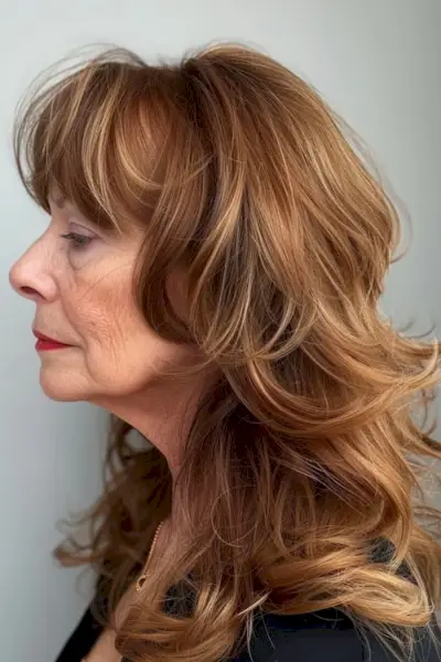 50歳以上の女性のための前髪のある栗のレイヤーの長いヘアスタイル。