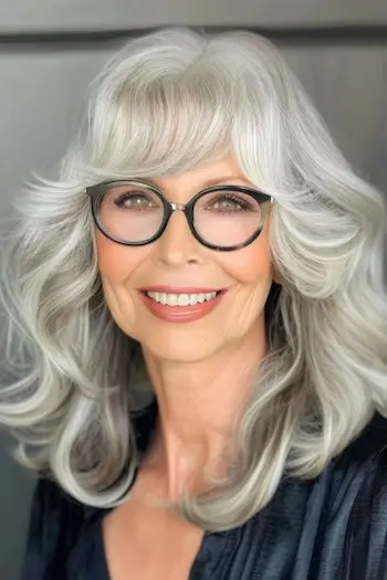 Vrstvené vlny s ofinou a brýlemi na usmívající se ženě ve věku 60 let.