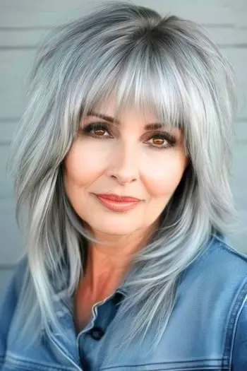 Středně dlouhé šedé vrstvy s ofinou na usmívající se ženě ve věku 60 let.
