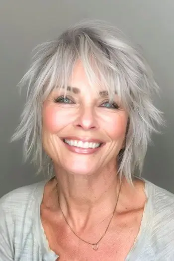 Oříznutý účes Silver Shag na usmívající se ženě ve věku 60 let.