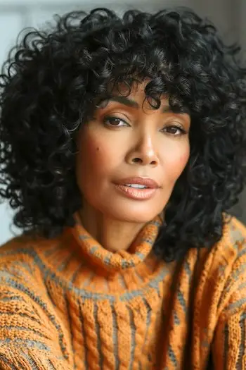 Kudrnatý účes s ofinou pro ženy nad 40 let s hustými vlasy.