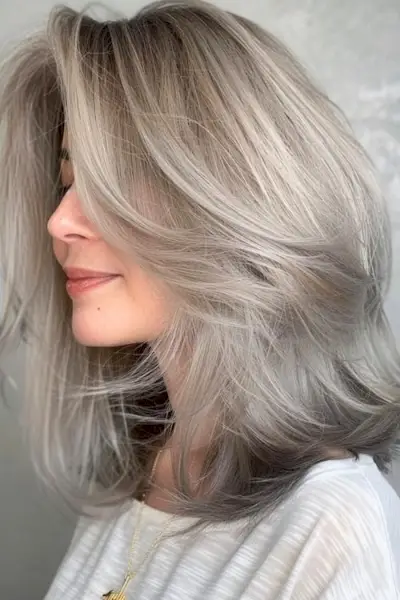 40歳以上の女性のためのうっすらとしたシルバーレイヤーのミディアムレングスのヘアスタイル。