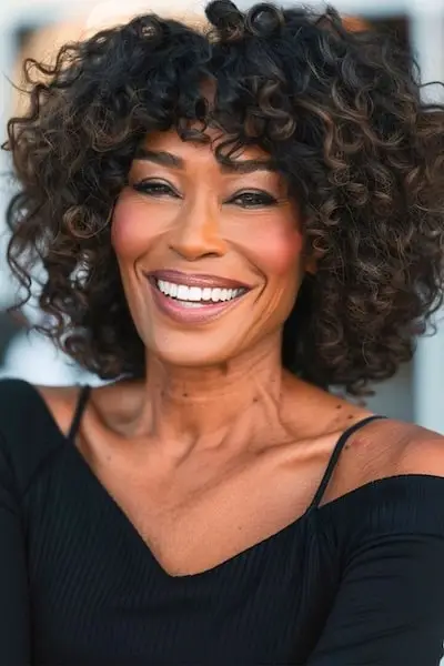 Natürliche Locken mit Pony-Frisur für Frauen über 60.