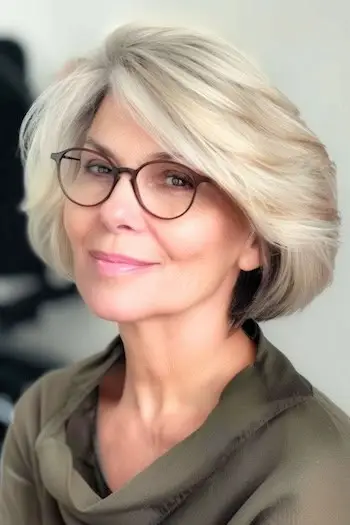 Obszerne warstwy z zaczesaną na bok grzywką Krótka fryzura dla kobiet po 50. roku życia w okularach.