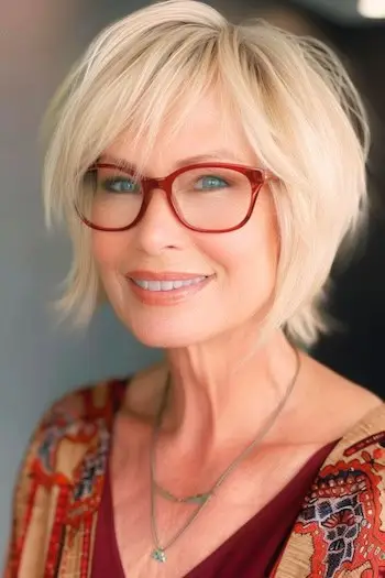 Przycięta, skośna fryzura z warstwami Krótka fryzura dla kobiet po 50. roku życia w okularach.