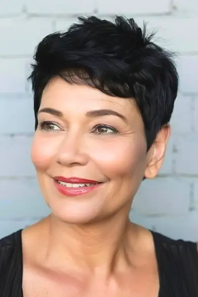 두꺼운 머리를 가진 50세 이상 여성을 위한 옆면이 잘린 질감 있는 픽시 헤어스타일.