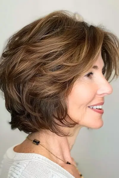 두꺼운 머리를 가진 50세 이상 여성을 위한 레이어드 깃털 밥 헤어스타일.