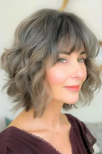 웃고 있는 60대 여성의 앞머리 헤어스타일을 레이어드한 웨이브.