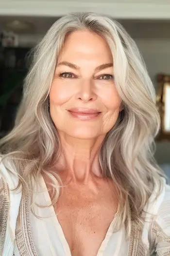 웃고 있는 60대 여성의 레이어드 루즈 웨이브 헤어스타일.