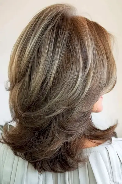60歳以上の女性のためのボリュームのあるレイヤーのミディアムヘアスタイル。