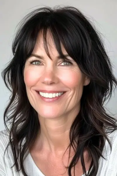 Dlouhý střapatý účes pro ženy nad 40 let s ofinou.