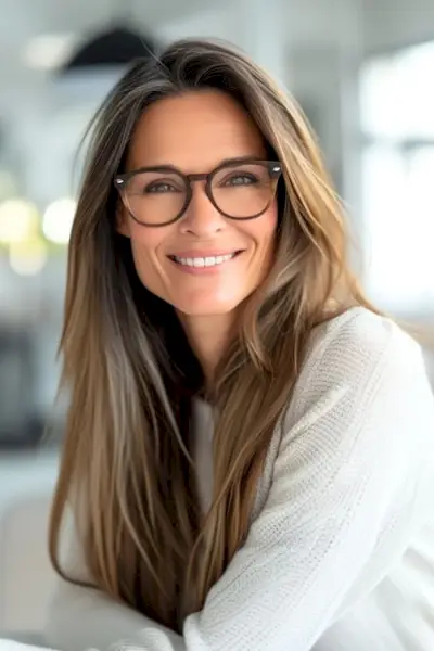 メガネをかけた60歳以上の笑顔の女性に長くまっすぐなレイヤー。