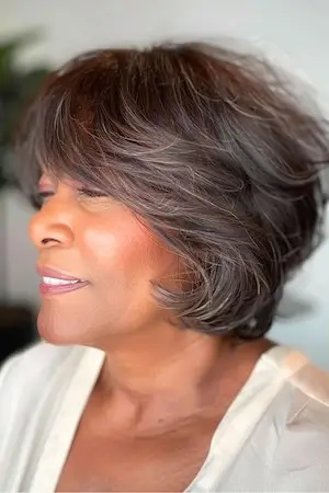 둥근 얼굴을 가진 50세 이상 여성을 위한 짧은 깃털 레이어 헤어스타일.