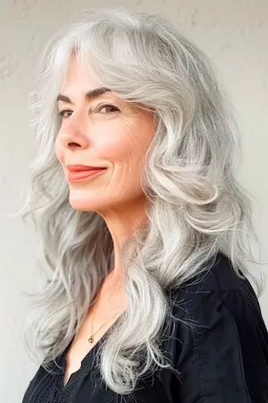둥근 얼굴을 가진 50세 이상 여성을 위한 긴 은색 웨이브 헤어스타일.
