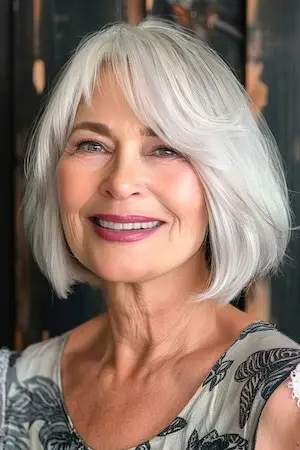 둥근 얼굴을 가진 50세 이상 여성을 위한 희미한 앞머리가 있는 밥 헤어스타일.