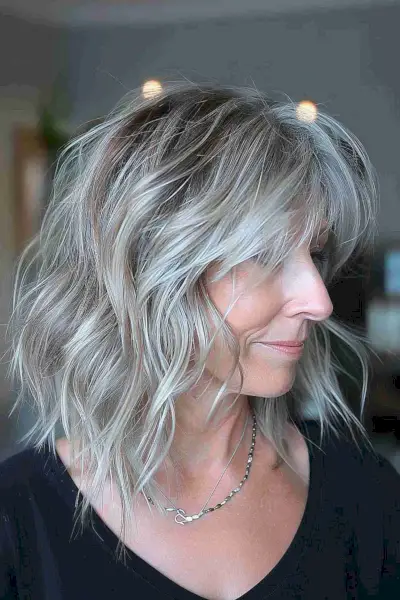 Medium-length layered silver-blonde hairstyle with soft waves for sophisticated women over 40
