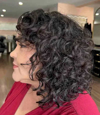Shoulder-Length Curly Haircut with Curly Bangs for an Old Lady