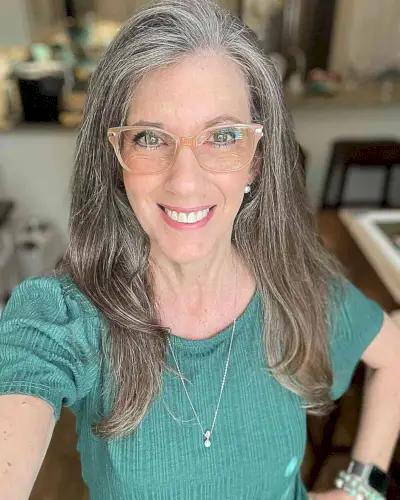 Long Silver Hair with Side Part and Lots of Layering on a woman in her fifties with glasses