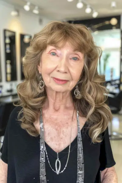 Woman with mid-length wavy hair featuring bangs, suitable for women over 70.