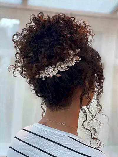 Kinky Bun Updo with Face-Framing Curls and a Floral Hair Wrap for prom