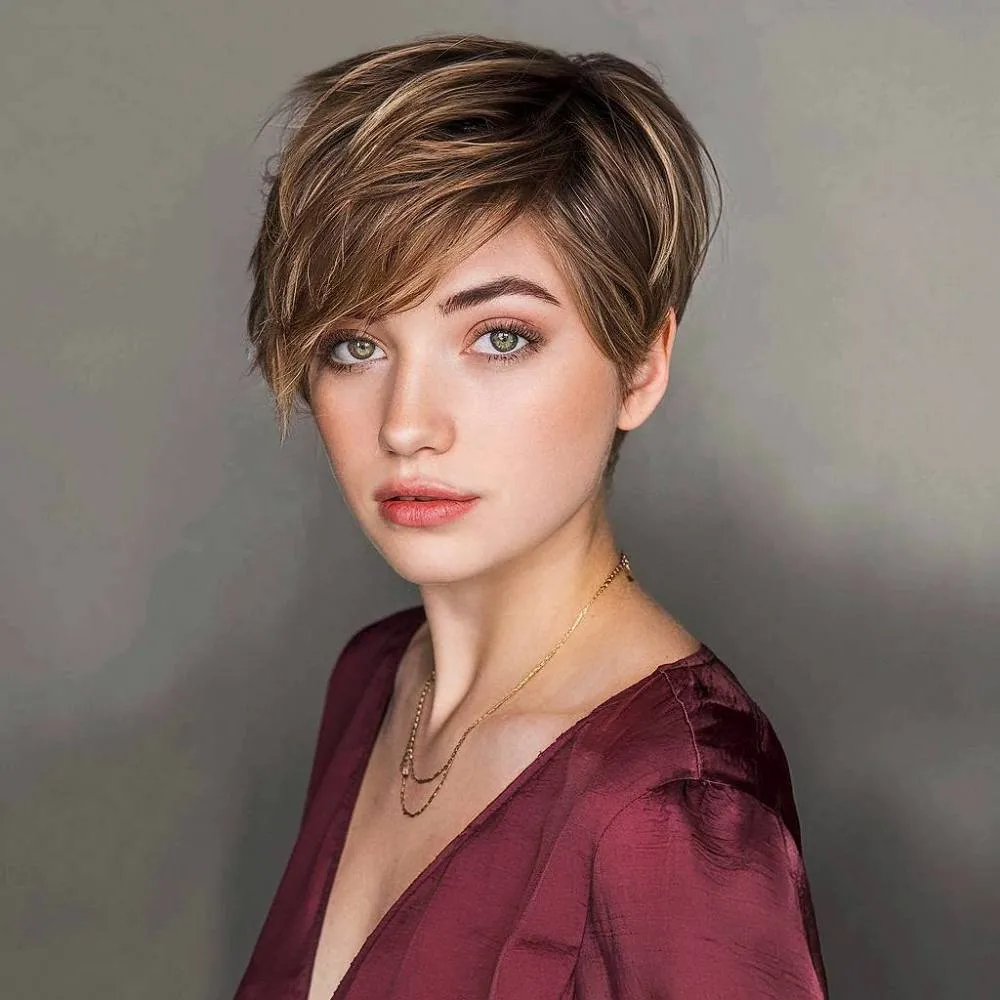 Corte pixie morena quente com camadas emolduradas no rosto e franja suave lateral para um estilo atemporal' title=