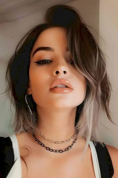 Stylish woman with neck-length tousled layered haircut and dark roots