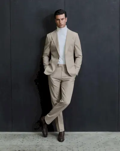 Créez un ensemble serein avec un costume de couleur claire et un pull à col roulé.