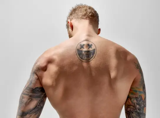 Nasmejani moški s tetovažo hrbtne lobanje