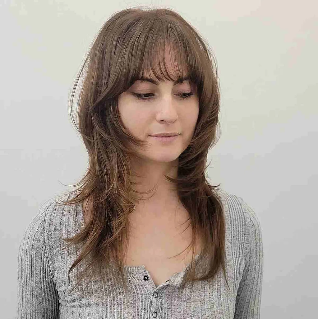 うっすらとした前髪と長めのレイヤーを持つウルフヘア' title=