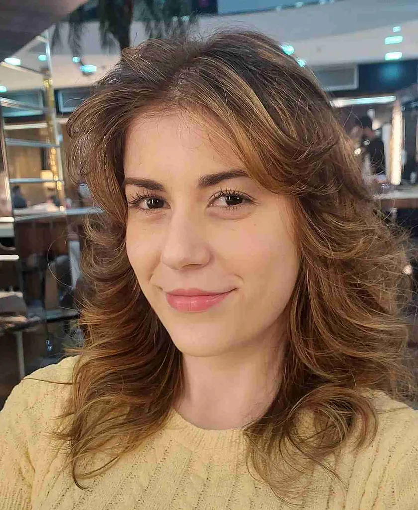 ミドルレングスのウルフカットヘアにフェザーレイヤーと前髪' title=