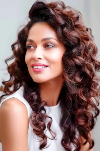 Acconciatura riccia con riccioli lunghi ed elastici per donne sopra i 50 anni.