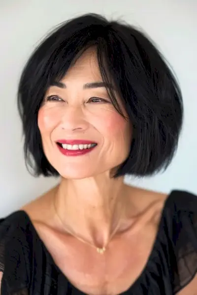 60대 여성을 위한 턱 길이의 레이어드 블랙 보브 헤어스타일입니다.