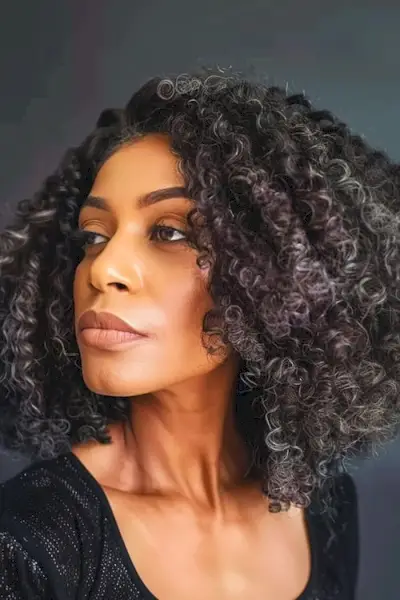 60代女性のためのナチュラルブラックレイヤードコイルカールヘアスタイル。