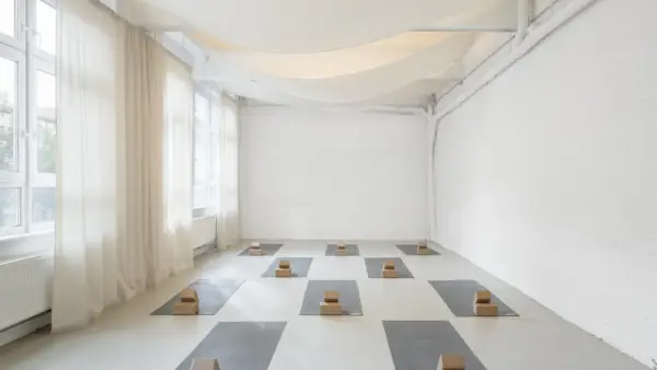all-white yoga studio space with a wall of windows and gauzy white curtains
